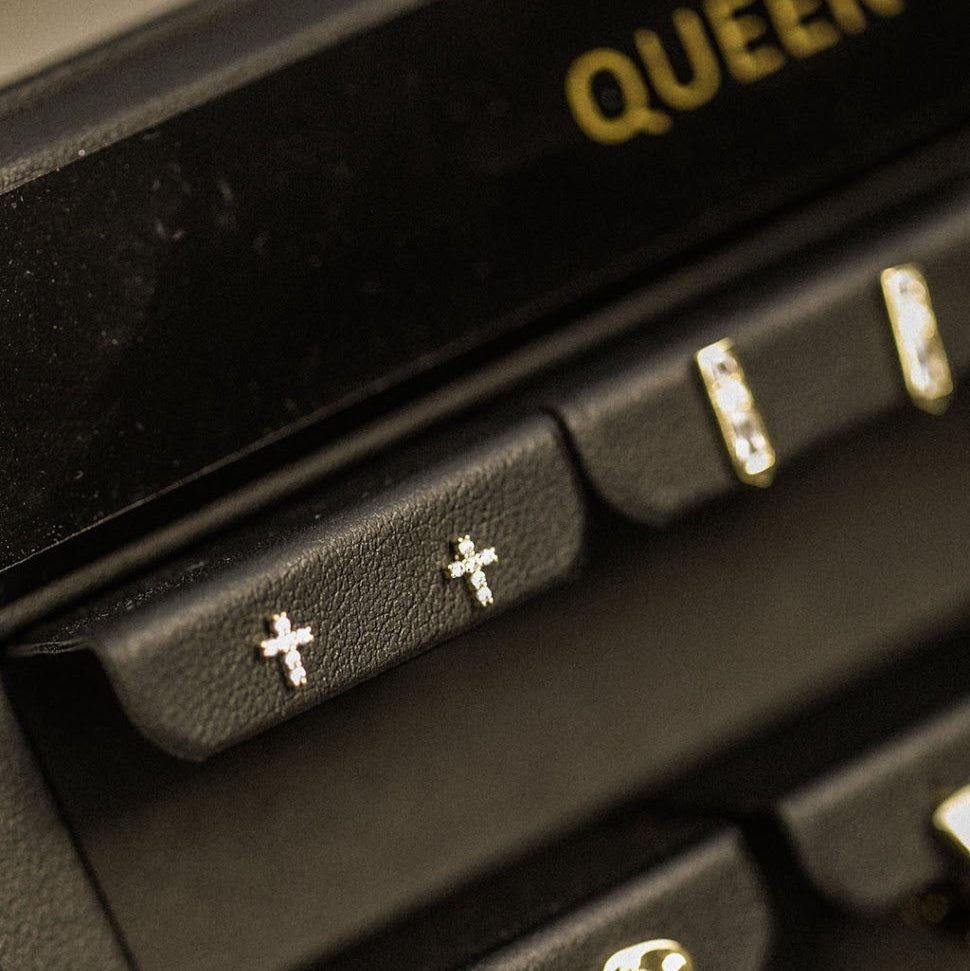 Gold earrings in a black jewelry box with 'QUEEN' branding.