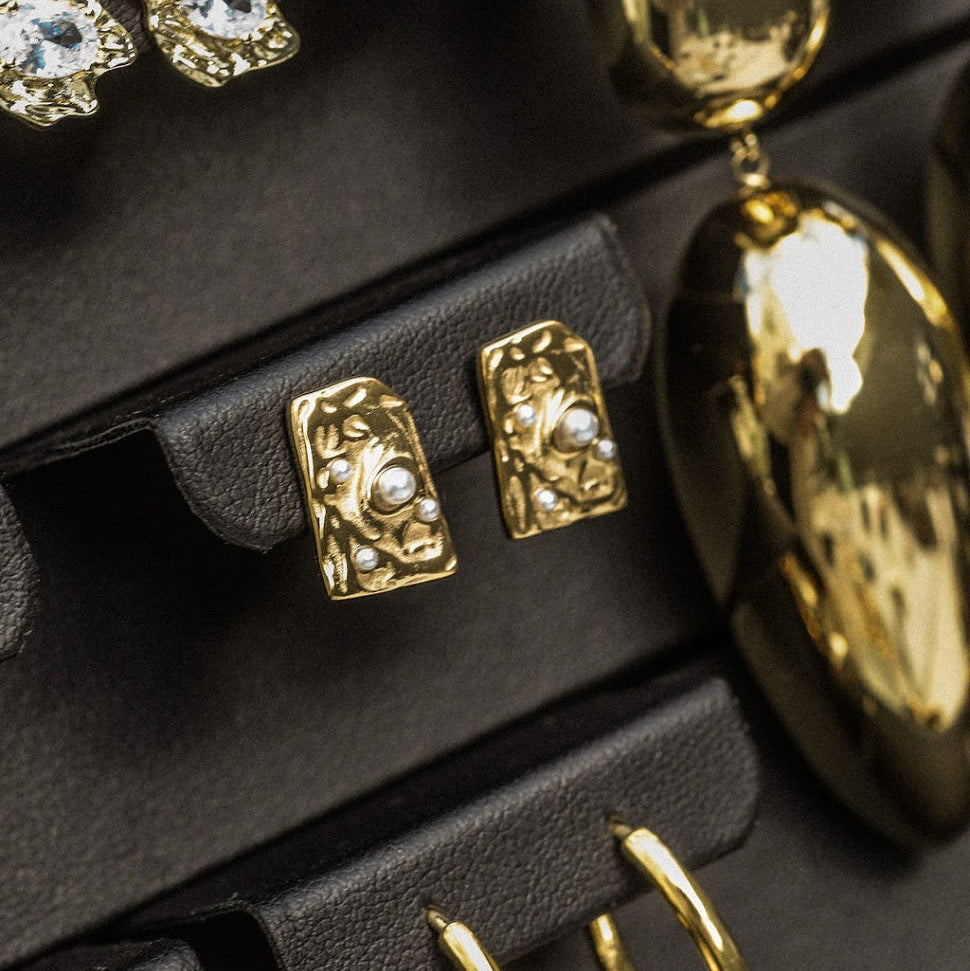 Gold earrings on a black earring stand