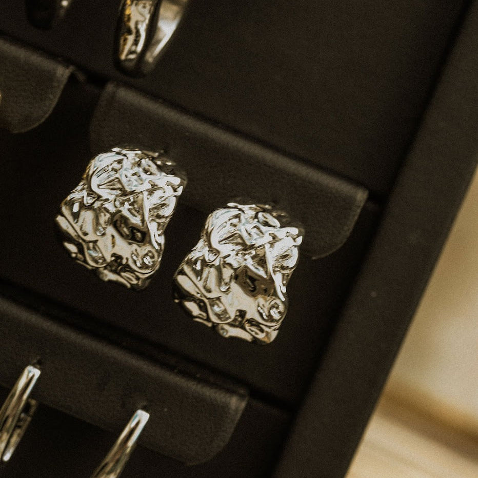 Silver earrings on a black jewelry display