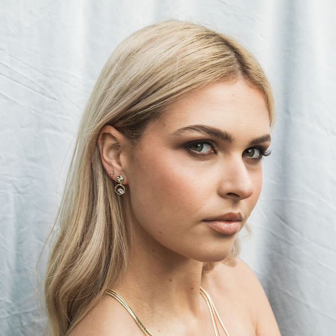 Woman with blonde hair and earrings against a light background