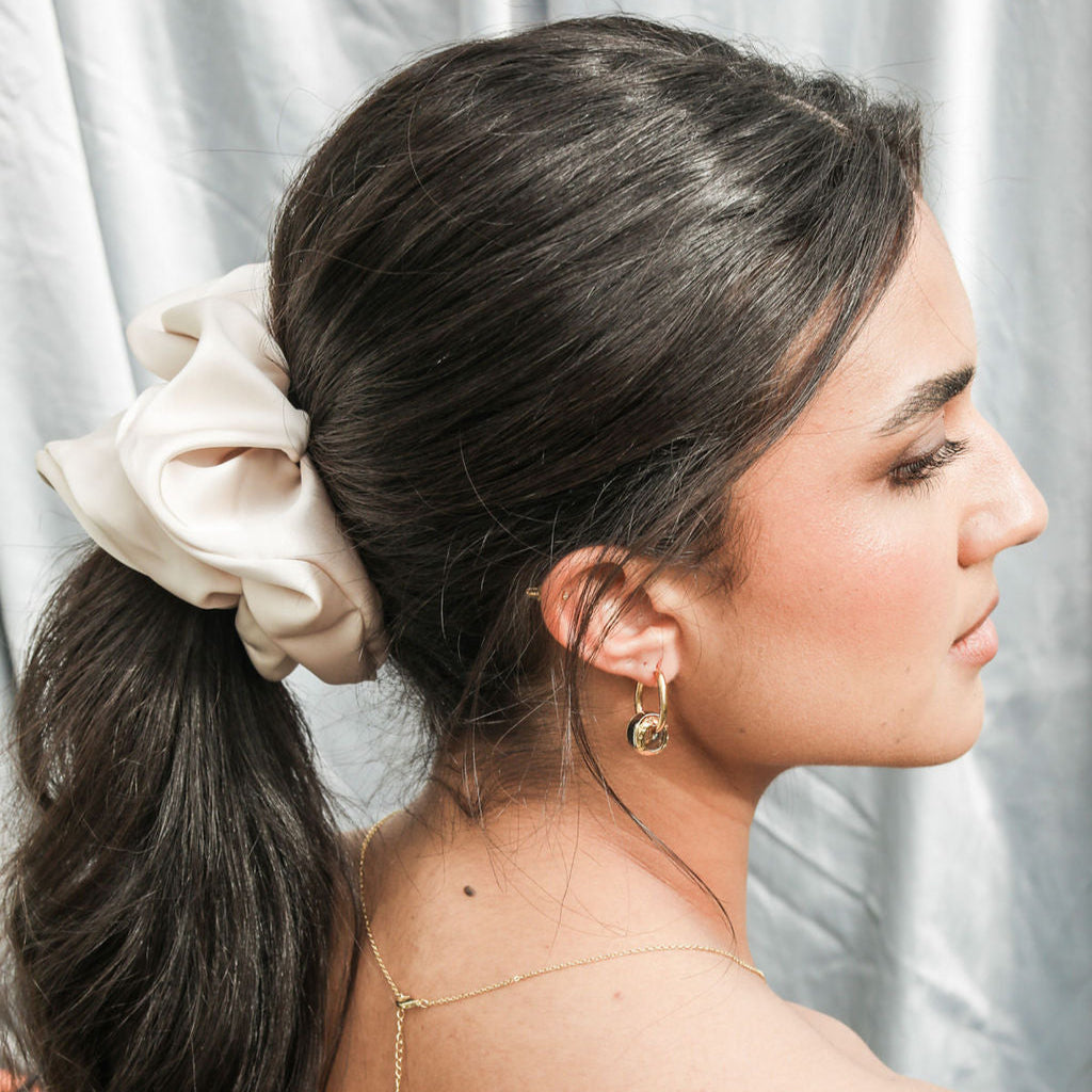 Woman with a ponytail and decorative hair accessory against a neutral background