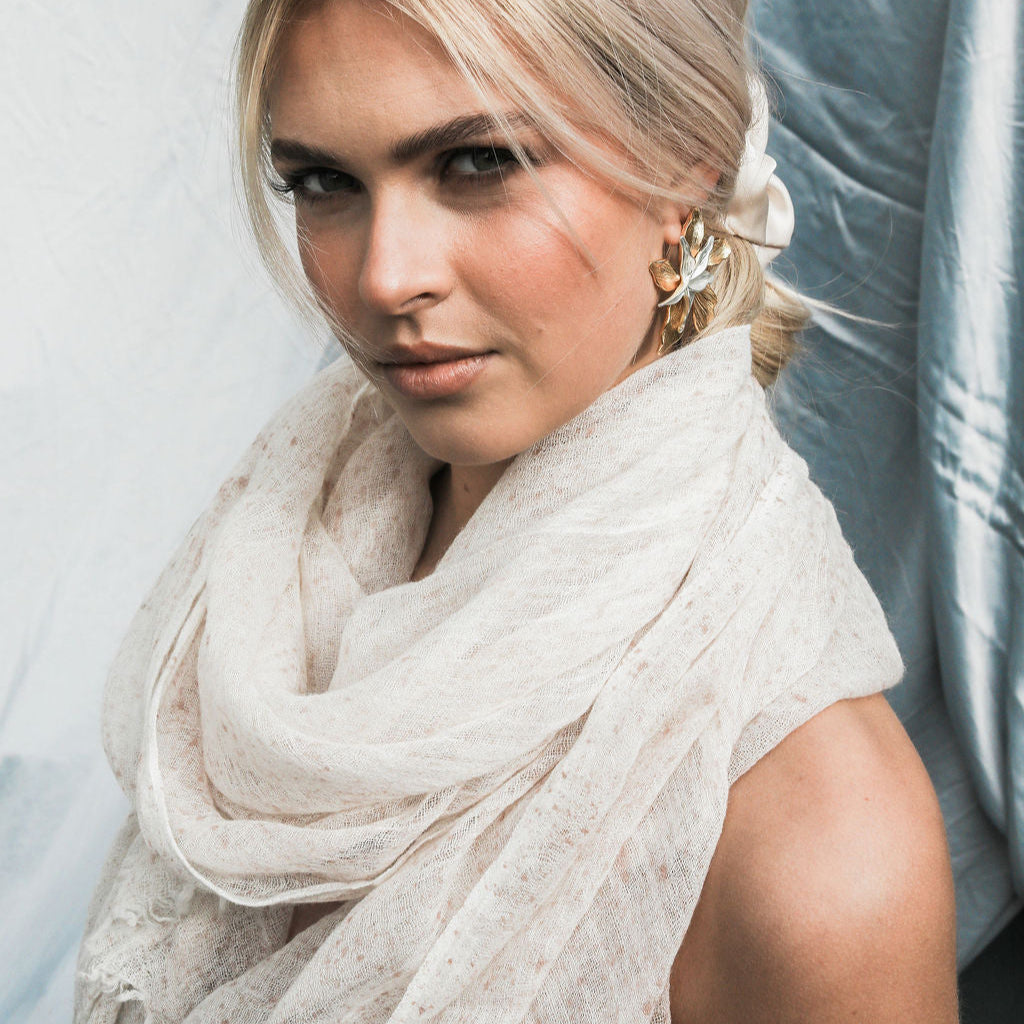 Woman wearing a light pink colored scarf against a neutral background