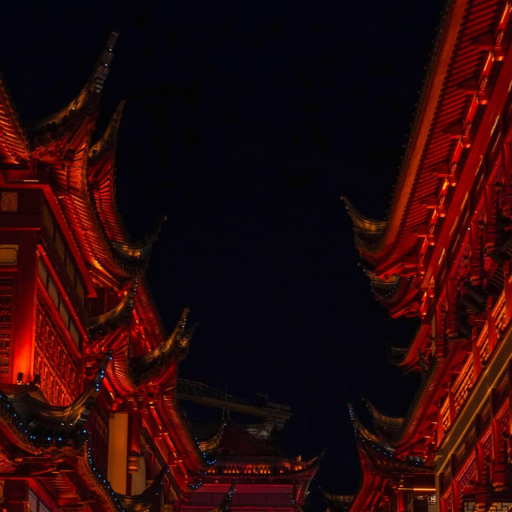 Traditional Chinese architecture with vibrant red and blue lighting at night.