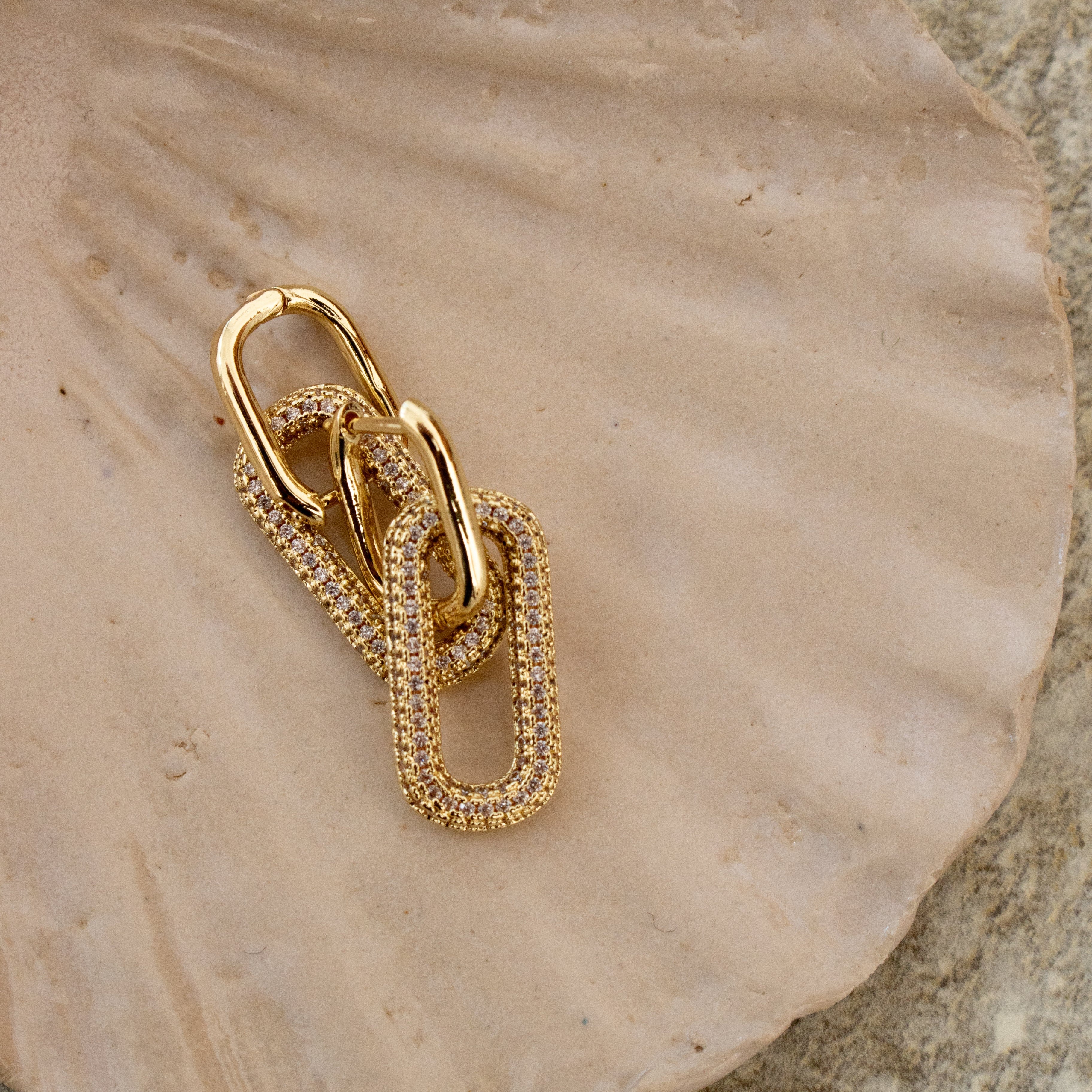 Gold and zirconia earrings on a shell