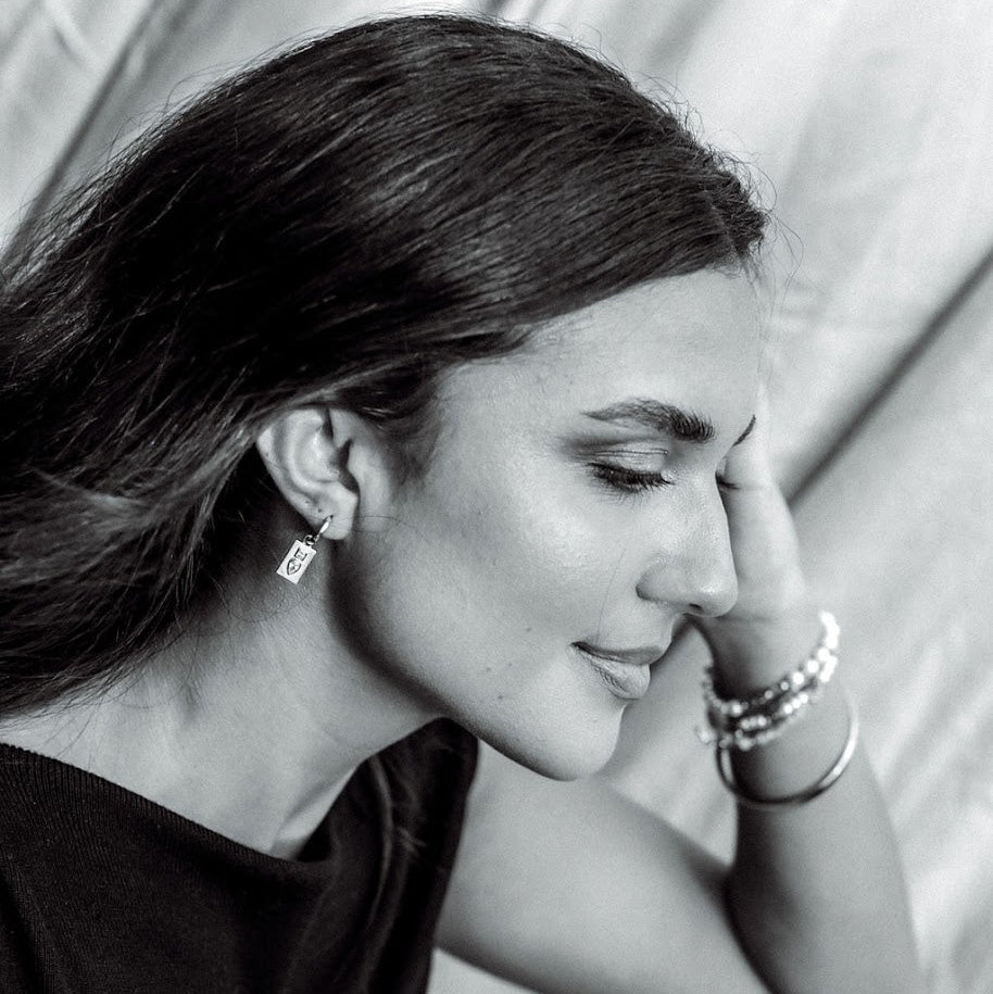 Black-and-white photograph of a model wearing a Dewdrop Sleeper Earring with her hair tucked behind her ear.
