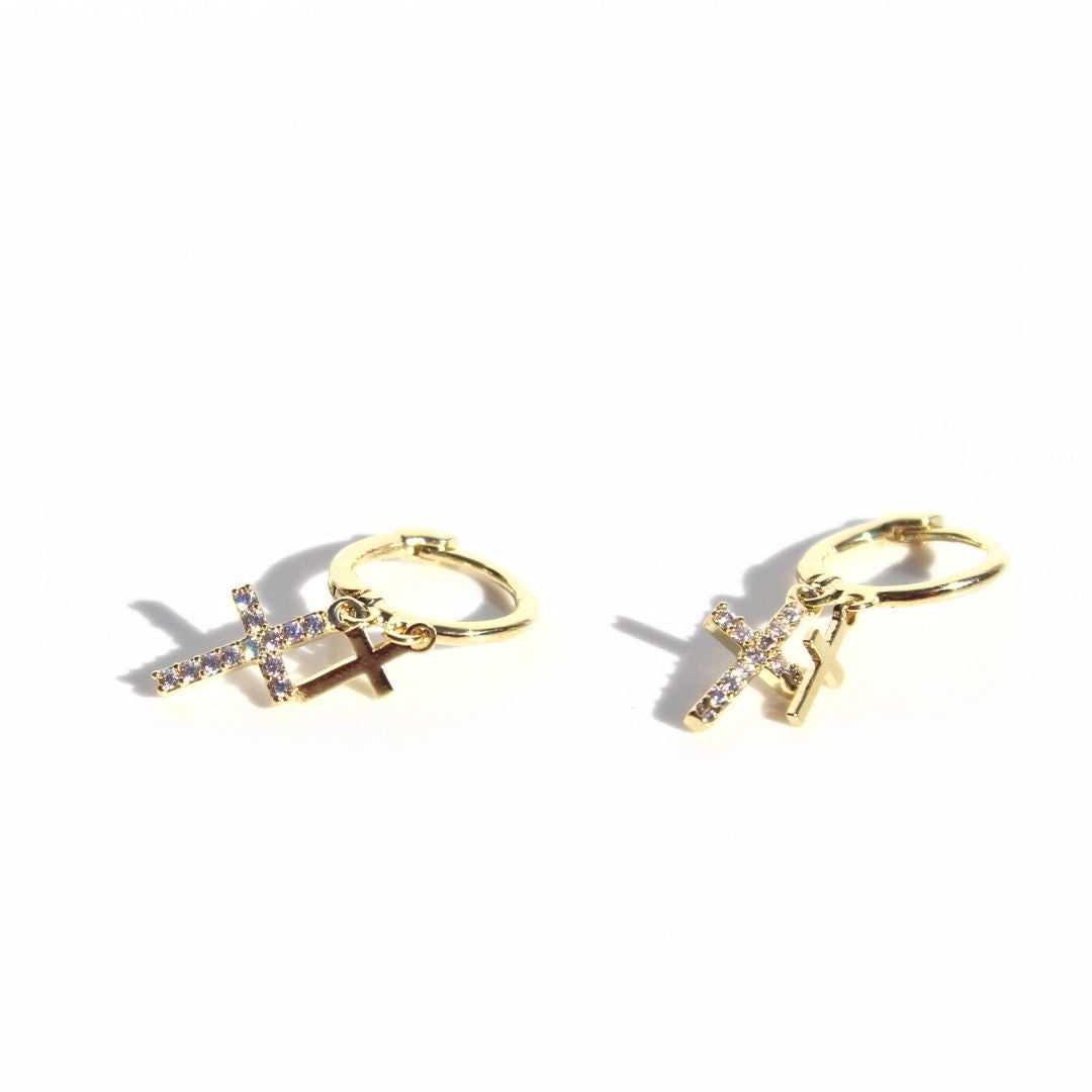 Gold Double Cross Sleeper earrings with overlapping polished and clear zirconia-set cross charms on a white background.