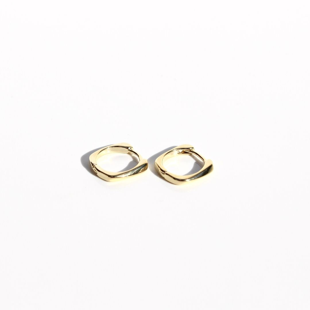 Two petite gold sleeper earrings side by side on white, showing their polished flattened profile and hinged closures.