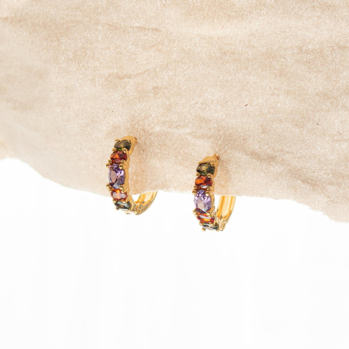 Gold Rainbow Sleeper Earrings displayed beneath pale stone, showing olive-green, orange and lavender zirconias.