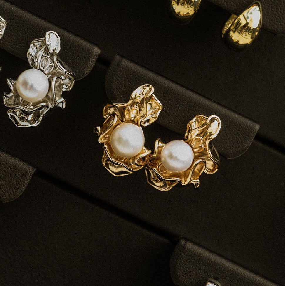 Gold Ruched Pearl Earrings on a dark jewellery tray, showing natural pearls framed by rippled gold settings.