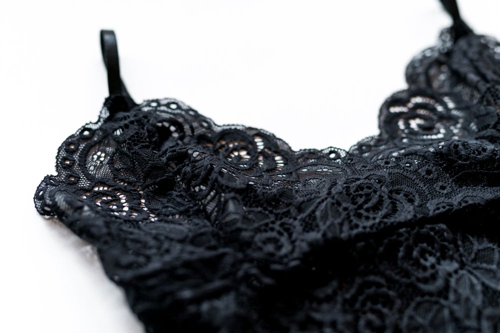 Close-up of the black bralette’s raised floral lace, scalloped neckline and slim shoulder strap.