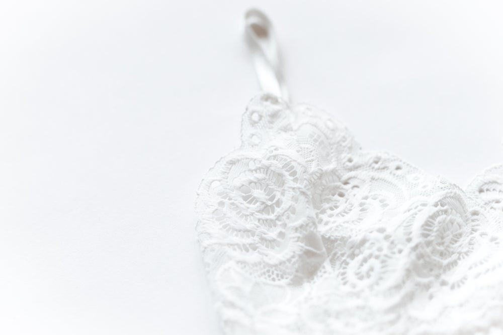 Close-up of the white bralette’s raised floral lace, scalloped neckline and slim shoulder strap.