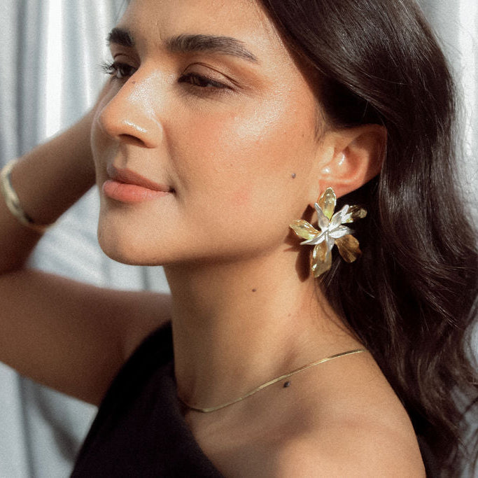 Woman wearing floral earrings with a neutral background