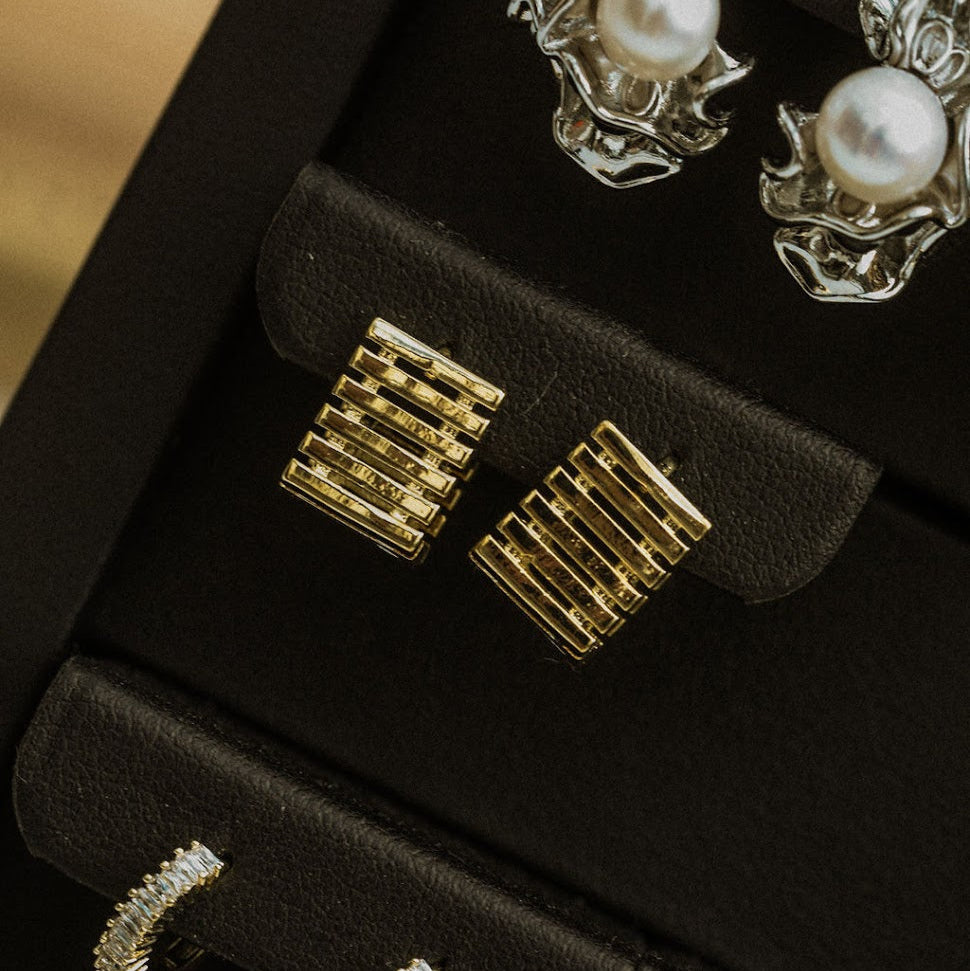 Gold and pearl earrings displayed in a jewelry box