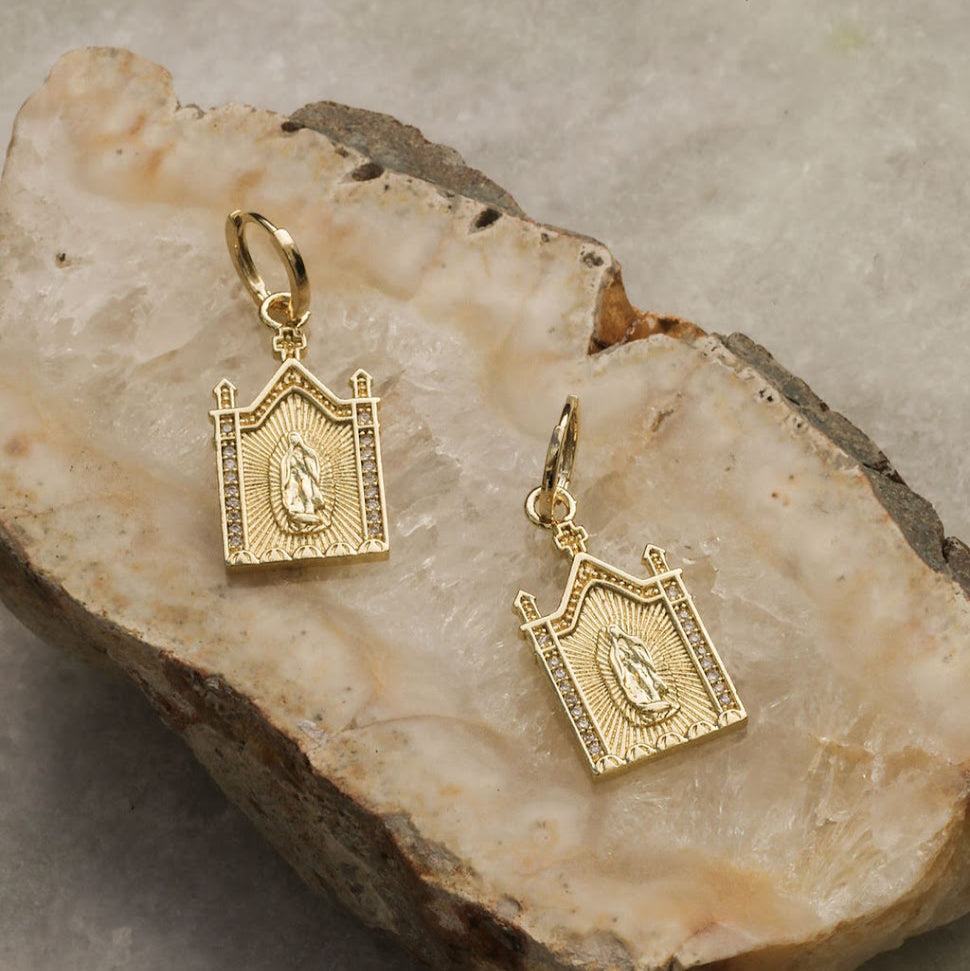 Gold earrings on a stone surface