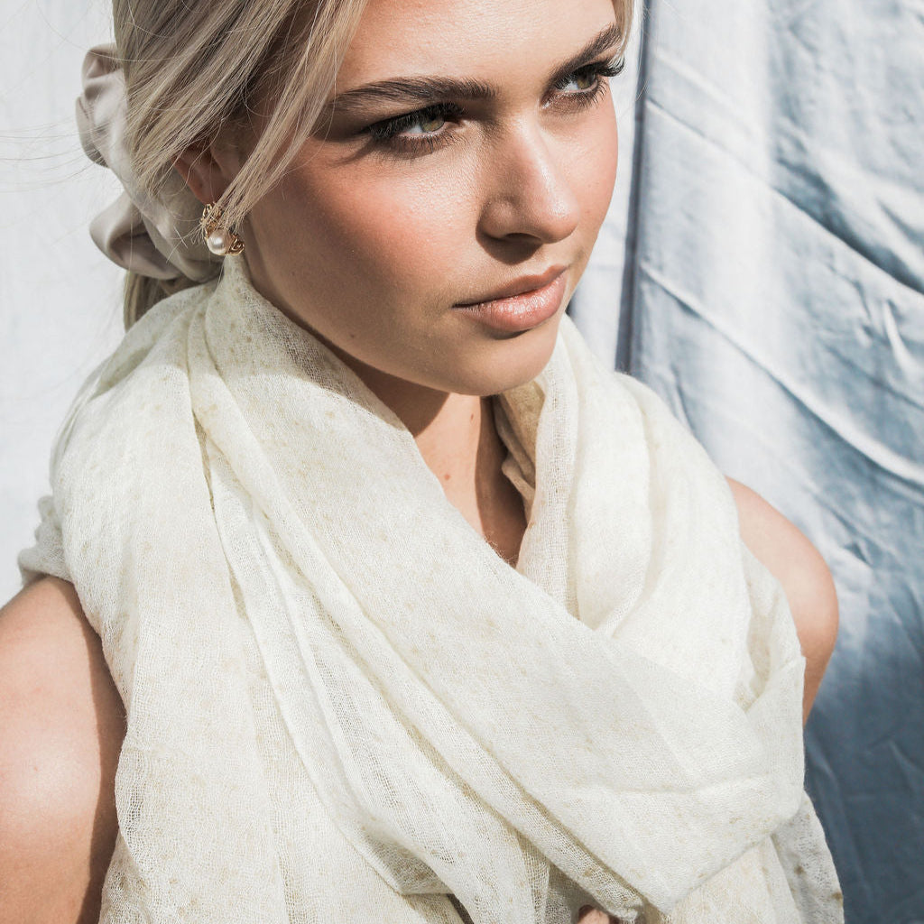 Woman wearing a cream scarf with a light background