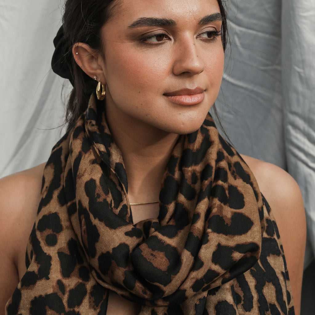 Woman wearing a leopard print scarf against a plain background
