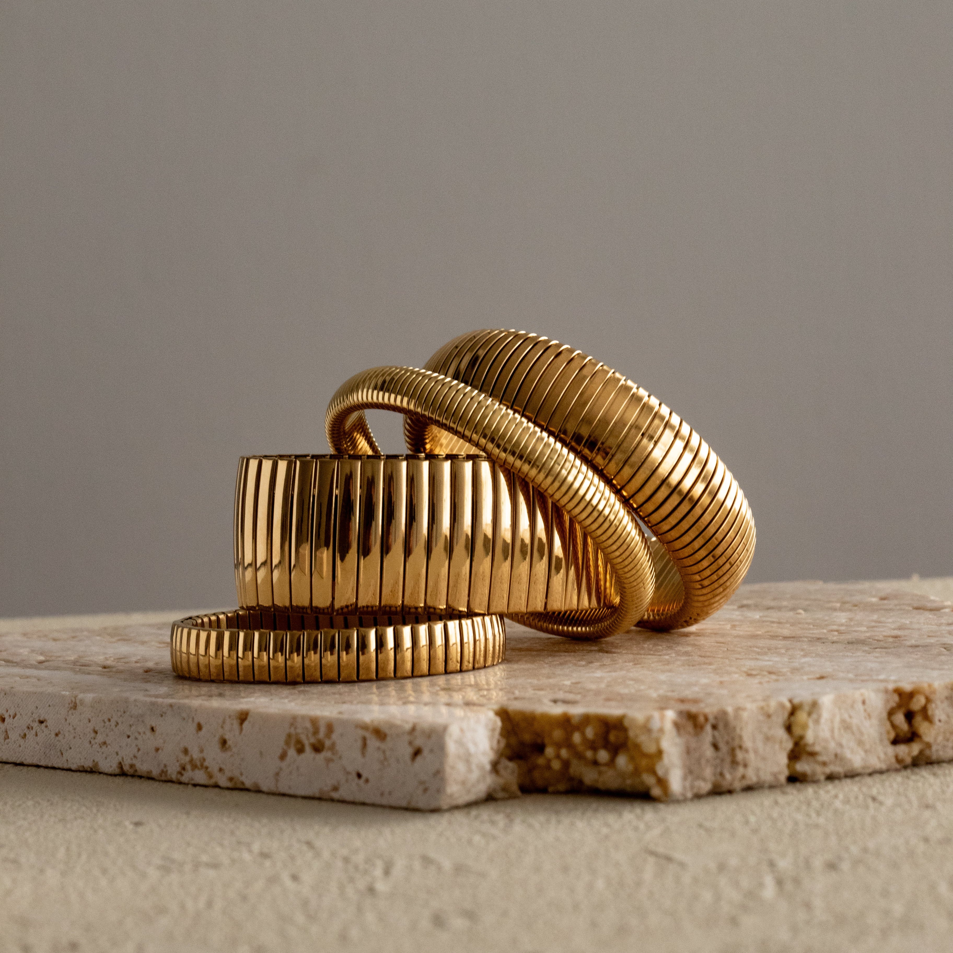 Gold bracelet son a textured surface with a neutral background