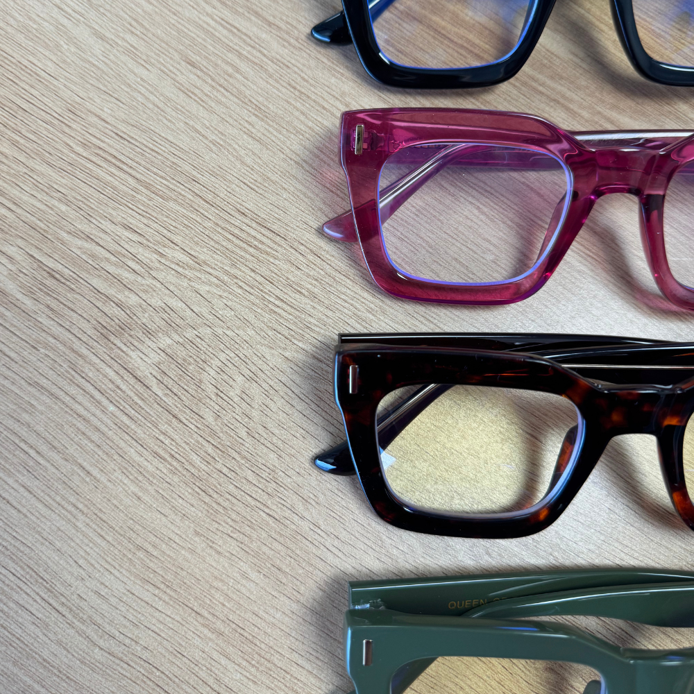 Four pairs of eyeglasses with different frames on a wooden surface
