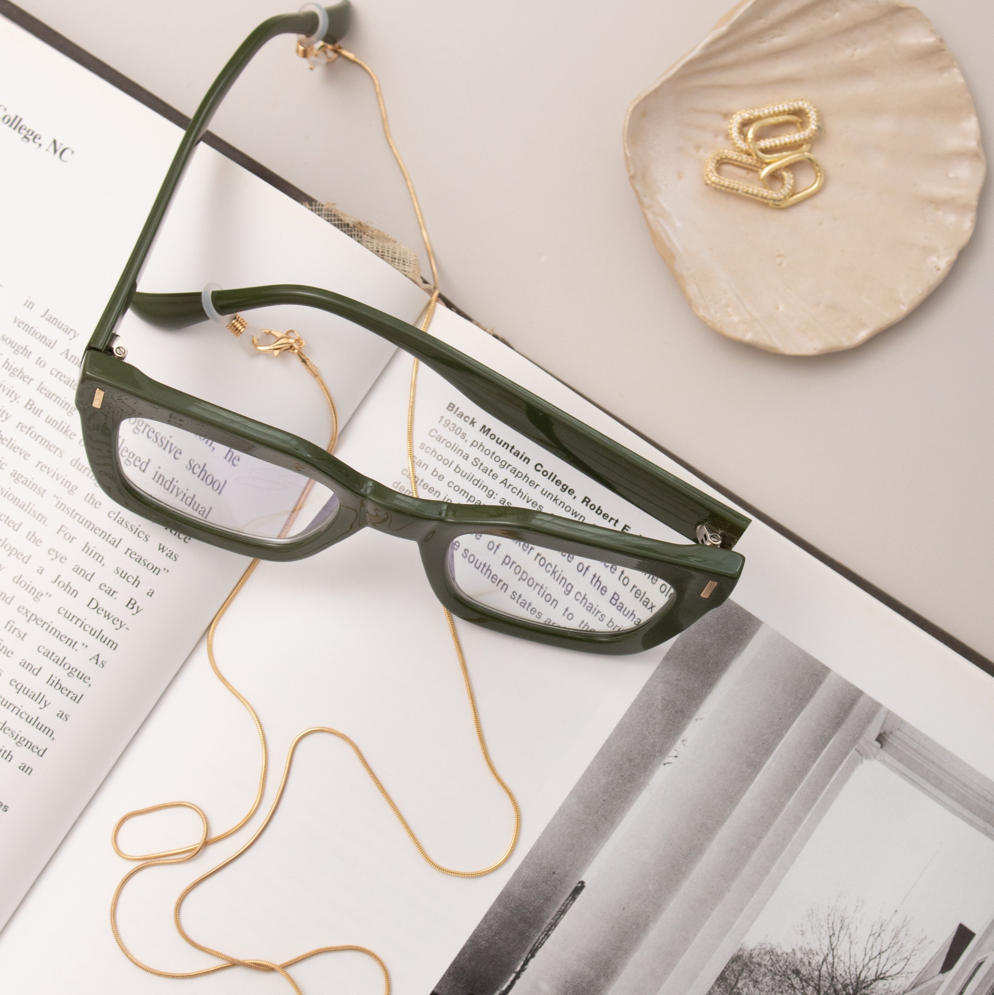 Green eyeglasses on an open book with a eye glasses chain with The Madison earrings  in the background