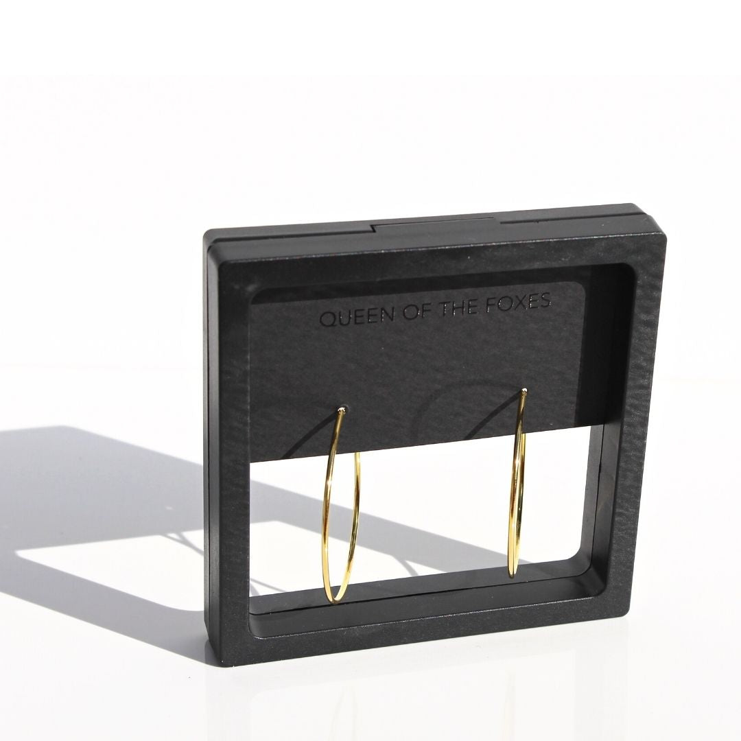 Fine gold hoop earrings displayed in black Queen of the Foxes presentation packaging.
