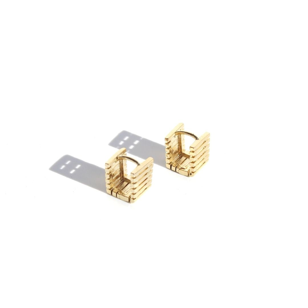 Angled view of gold Box Sleeper Earrings showing their square shape, ridged sides and hinged closures.