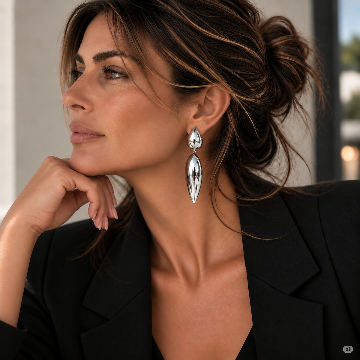 AI-created model looking left in a black blazer, showing the polished silver Origin earring with its long tapered drop.