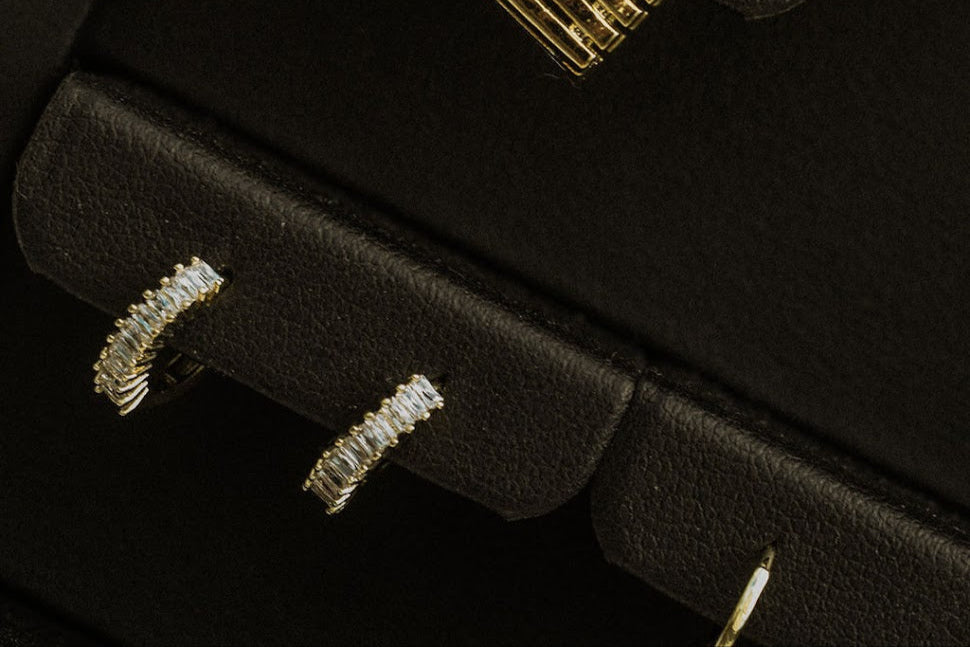 Close-up of gold Petite Marquise Sleepers on a black jewellery display, showing the clear zirconia settings