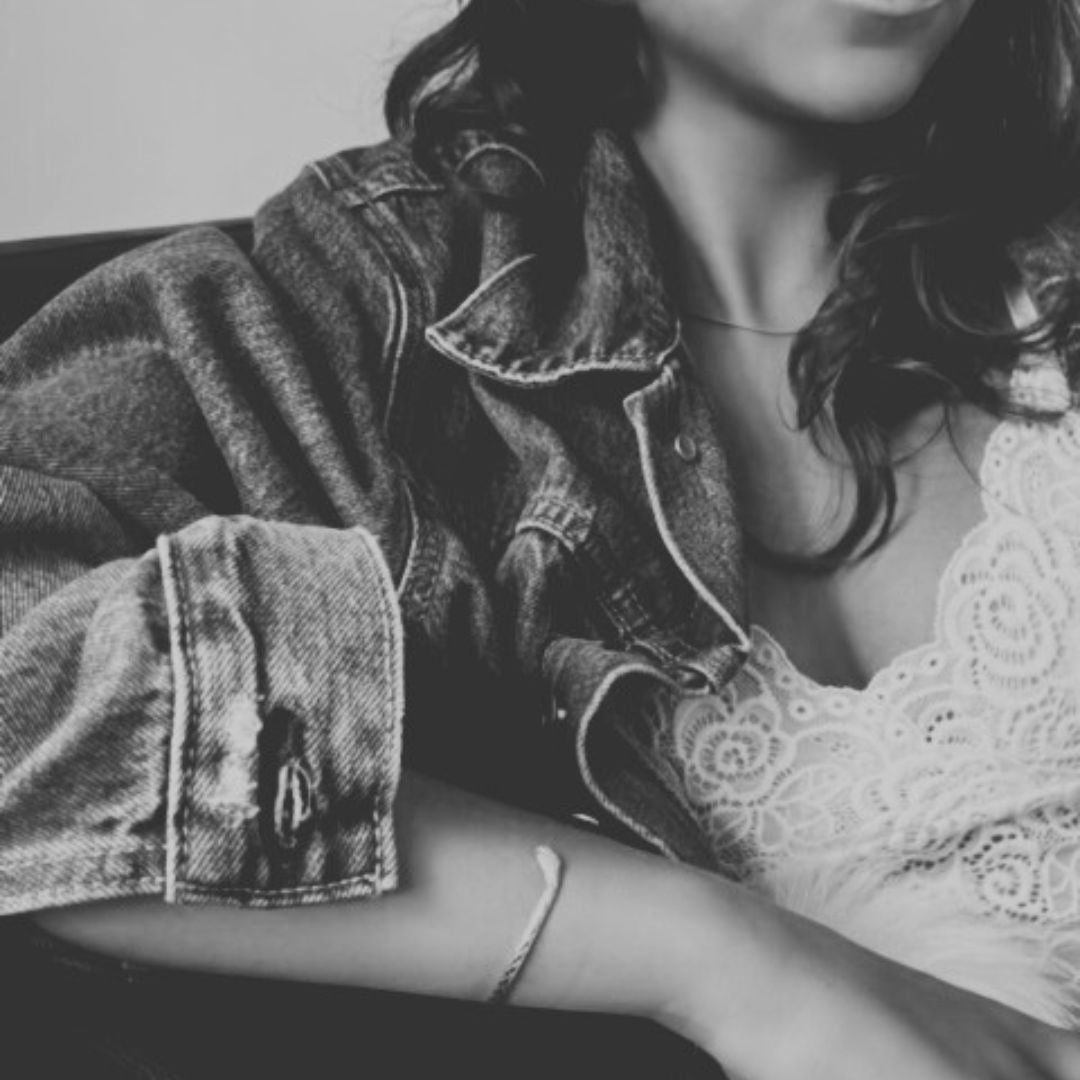 White floral lace bralette layered beneath a denim jacket, showing its scalloped neckline.