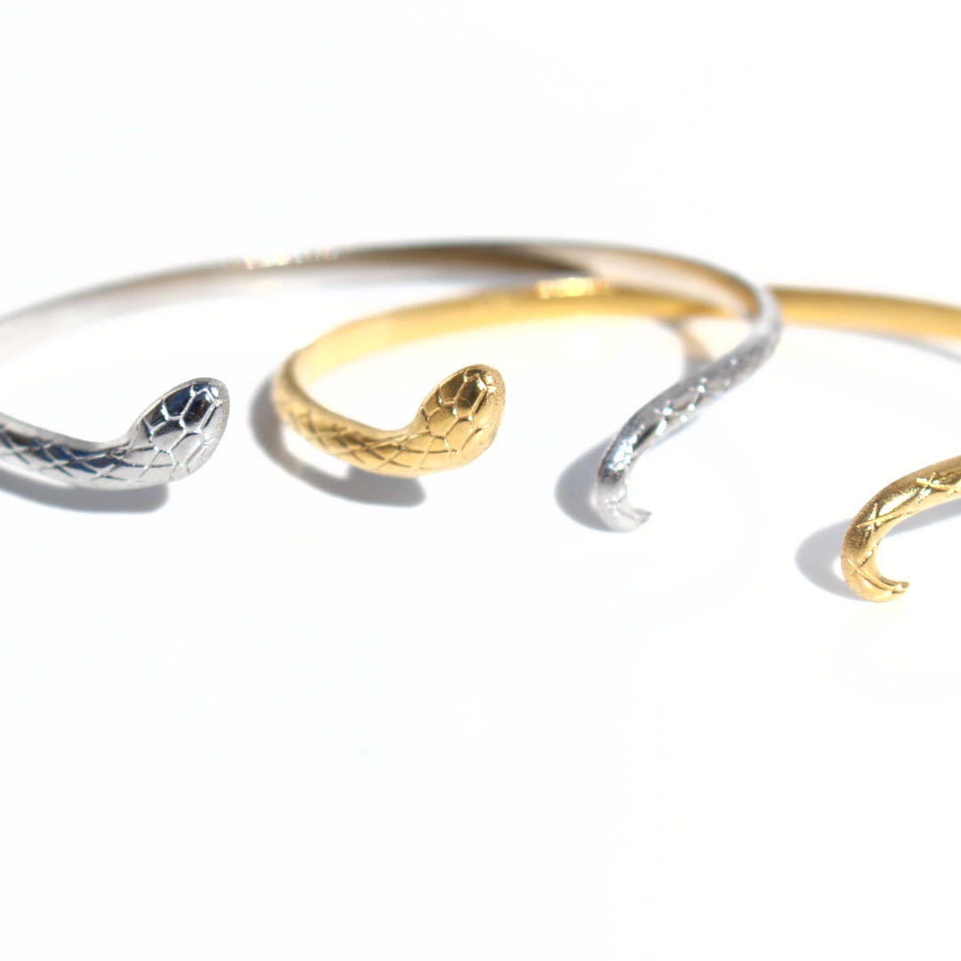 Gold sand silver snake cuff bracelets showing the textured serpent design and open-ended adjustable fit.