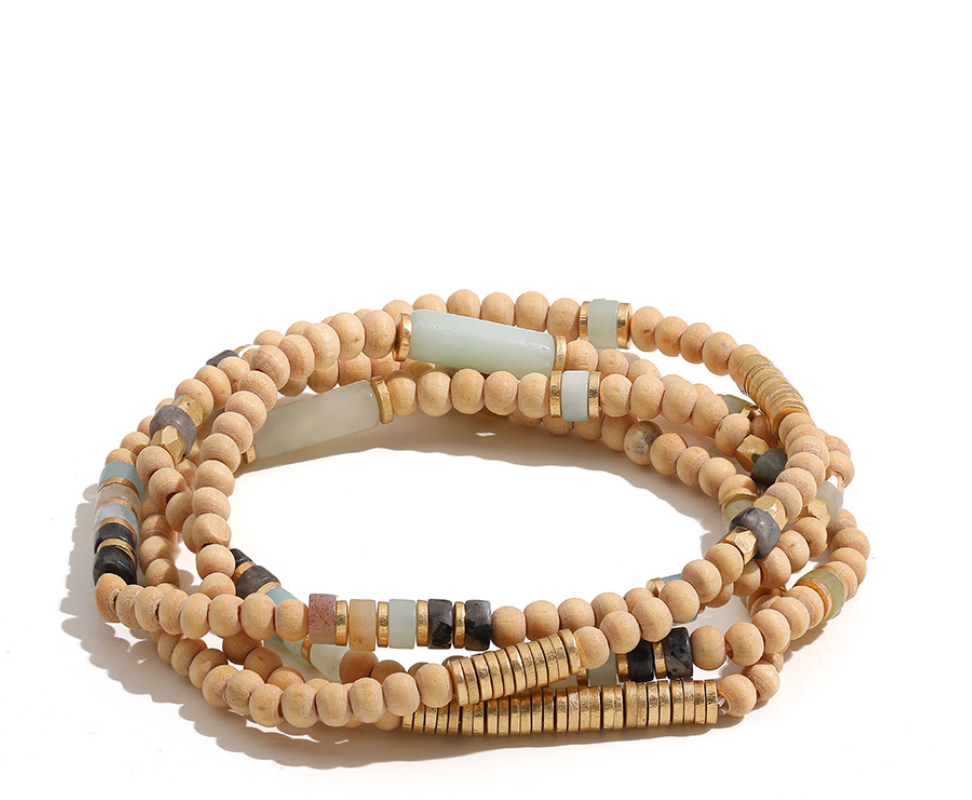 Natural Wood Wrap bracelet with pale wooden beads, muted sage accents and gold-tone disc spacers, coiled on white.
